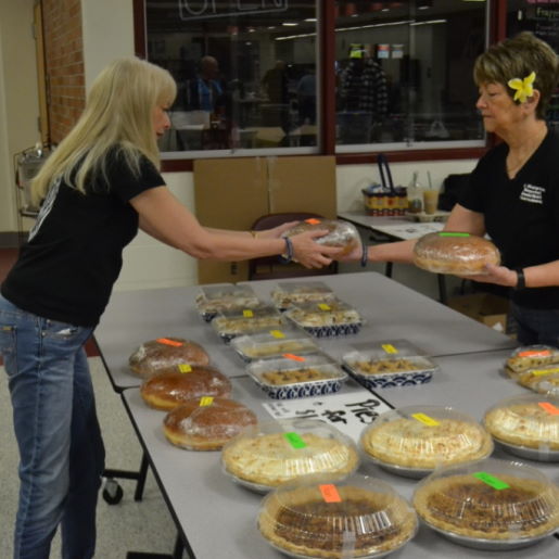 Two woman arranging pies on a table