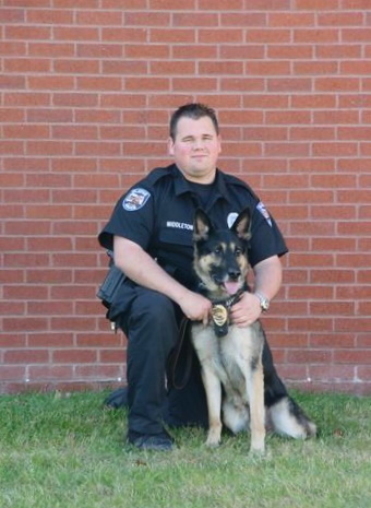 Cy in uniform posing with a German Shepard